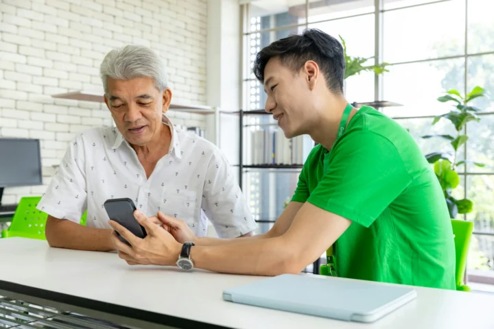 Two men checking an e-wallet app on a phone