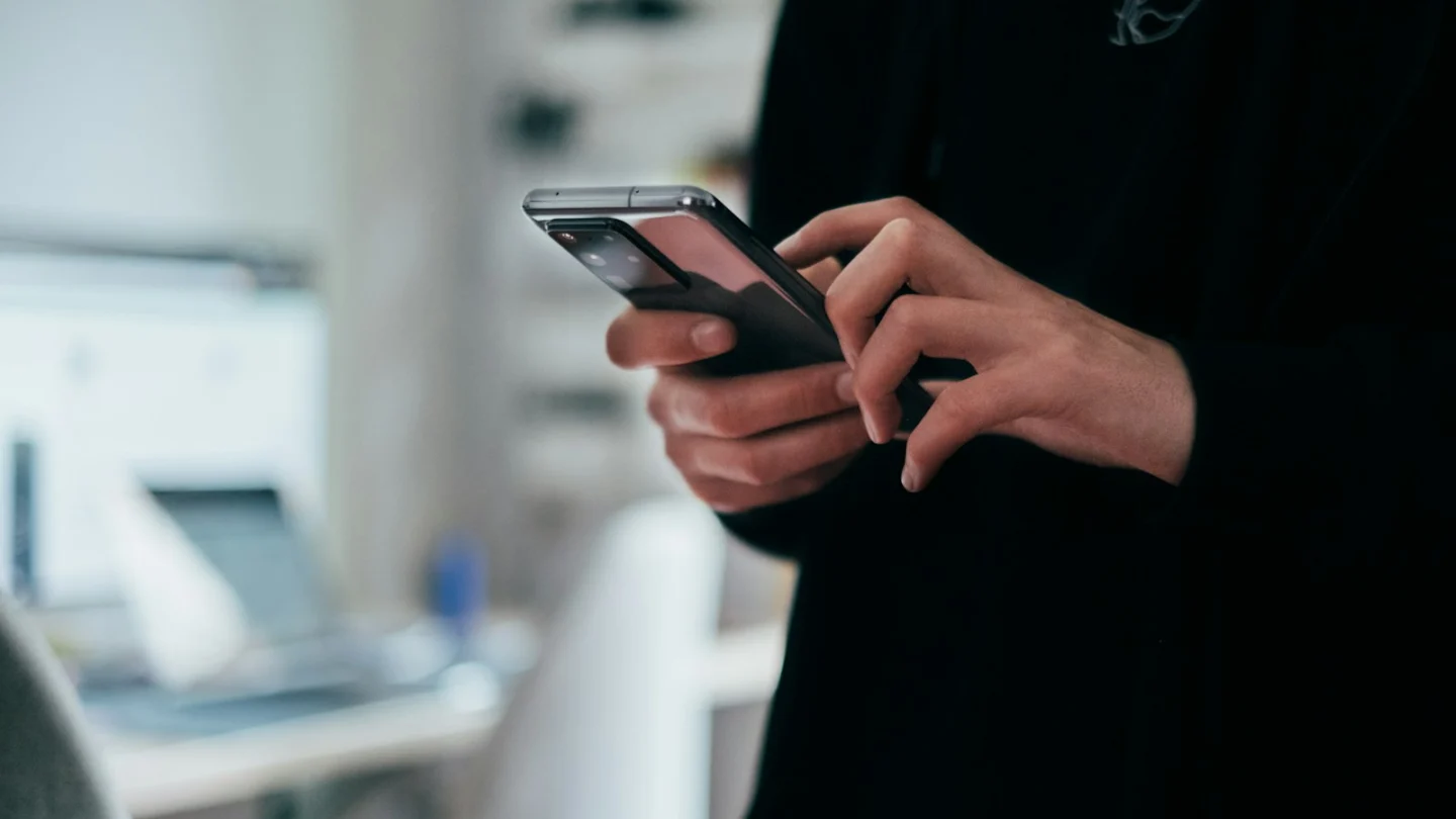 Close-up of a person's hands holding a smartphone and typing, representing unsolicited messages from online casino scam agents