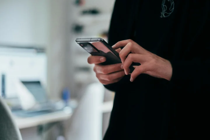 Close-up of a person's hands holding a smartphone and typing, representing unsolicited messages from online casino scam agents