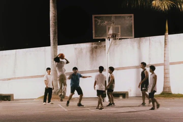 Pickup basketball game on an outdoor court at night